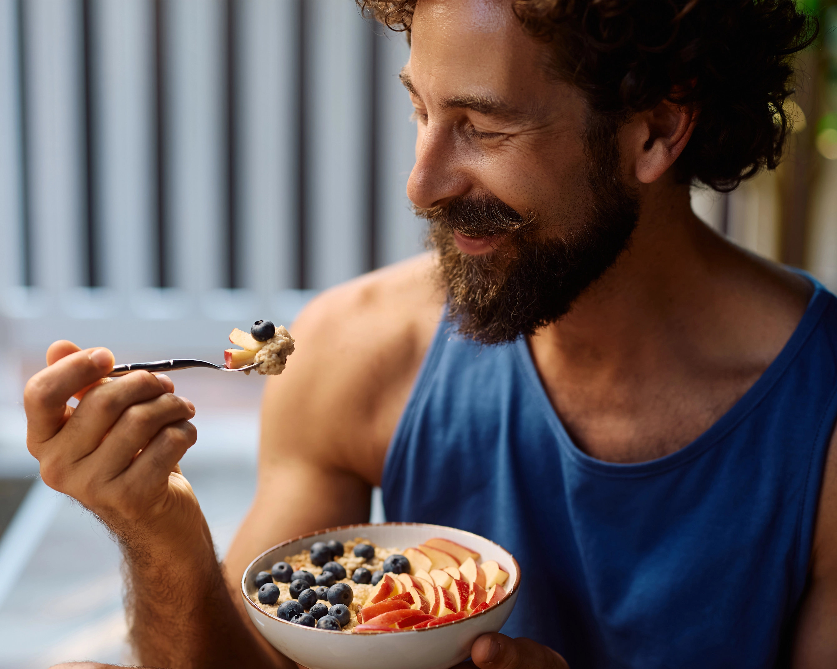 Mann isst Müsli mit frischem Obst als gesunde Mahlzeit